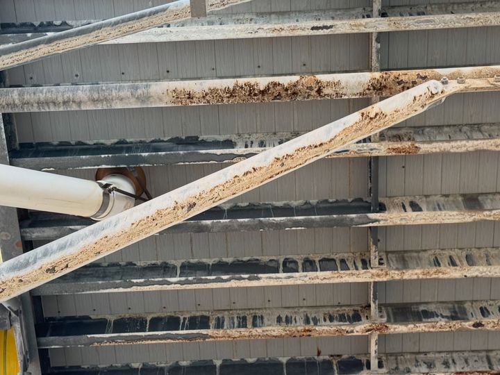 The underside of the old structure, steel crossmembers streaked with rust.