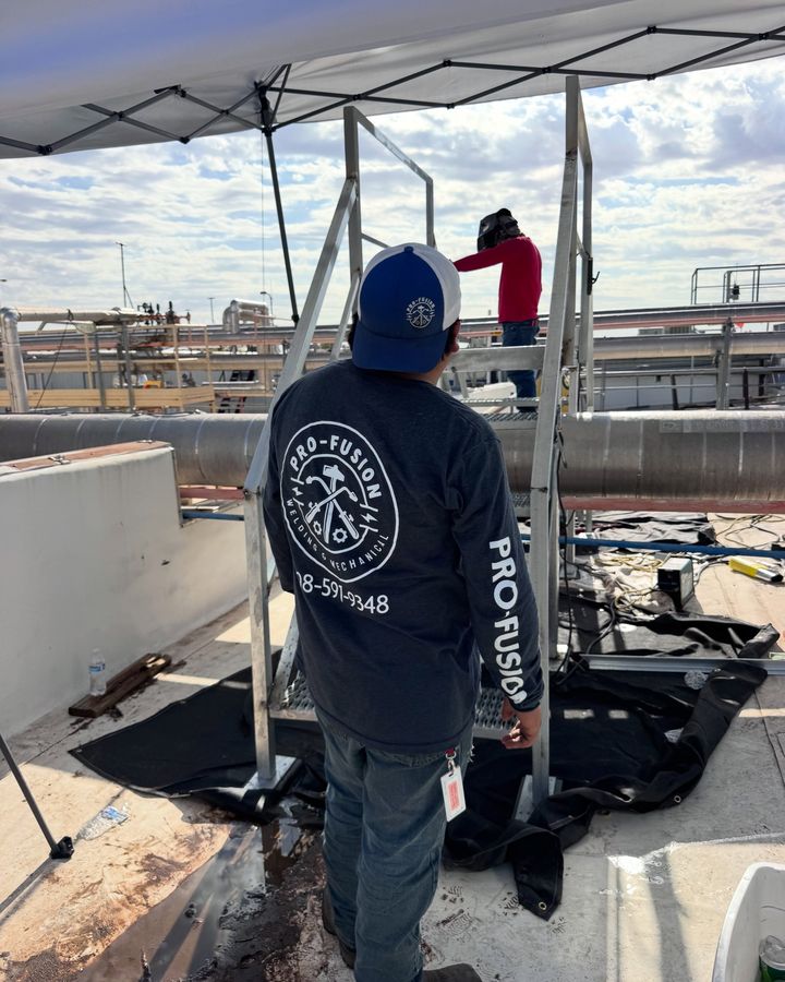 A crew member on a rooftop seen from behind, the Pro-fusion Welding & Mechanical badge and the number on the back of his shirt.